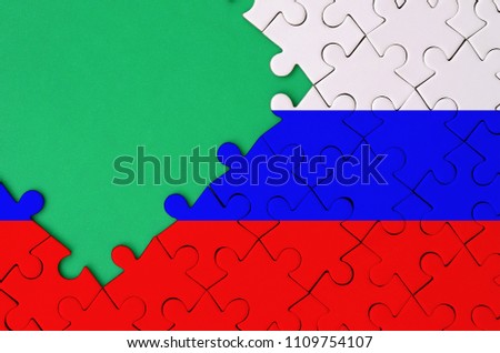 Russia flag  is depicted on a completed jigsaw puzzle with free green copy space on the left side
