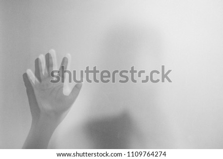 Shadow hands of the woman behind frosted glass.Blurry hand abstraction.Halloween background.Black and white picture