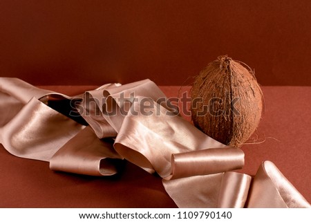 Still life of coconut and ribbon on brown background