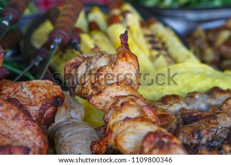 Fried meat of pig, lamb, grilled shish kebab with a delicious crust on the background of vegetables. Summer holidays and food in nature. Stock Photo

