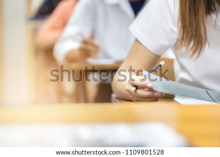 soft focus.hand high school or university student in uniform holding pencil writing on paper answer sheet.sitting on lecture chair taking final exam or study attending in examination room or classroom Royalty-Free Stock Photo #1109801528