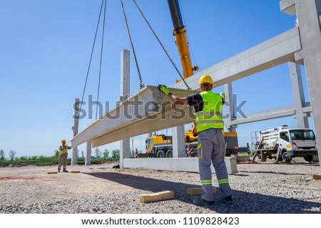 Workers are helping mobile crane to manage concrete joist for assembly huge construction. Royalty-Free Stock Photo #1109828423