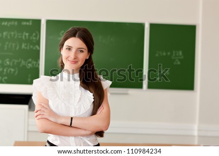 The teacher in the classroom on blackboard background.