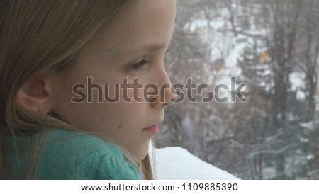 Sad Child Looking on Window, Kid Depressed, Unhappy Thoughtful Little Girl Face, Snowing Winter Day
