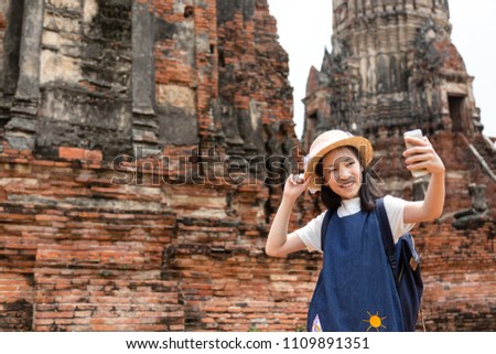 Cute happy smiling tourist girl taking self-portrait picture with smartphone,Wat Chaiwatthanaram is a Buddhist temple in the city of Ayutthaya Historical Park,Thailand, summer vacation,travel concept