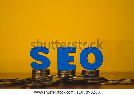 SEO text alphabet for Search Engine Optimization concept and coin money stack on wooden working table, business SEO.