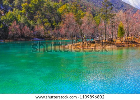 China Yunnan Lijiang Natural Park, clear lake, green mountains, yellow grass, blue sky