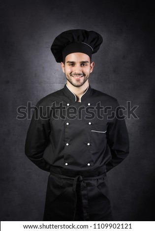 Portrait of a chef cooker in black uniform, gray background Royalty-Free Stock Photo #1109902121