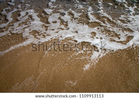 Sea foam and soft wave on a sand beach on the Italian island of Sardinia