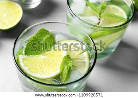 Refreshing beverage with mint and lime in glasses on table, closeup