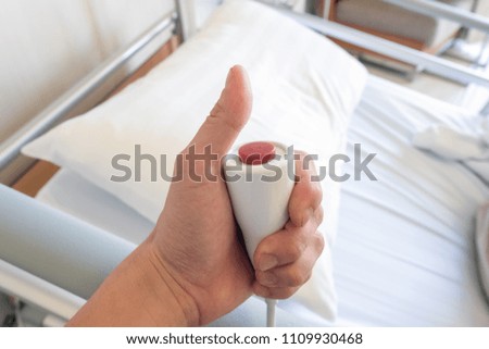 Hand pressing on emergency button on bed in hospital. signs for to call the nurse.
