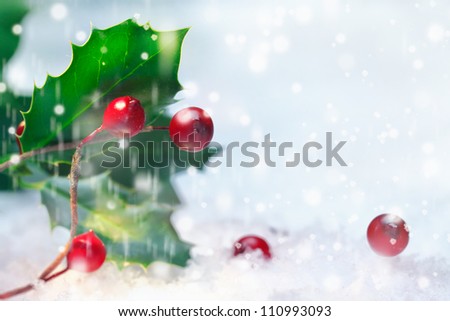 Christmas background of holly with red berries in falling snow with sparkling bokeh and copyspace