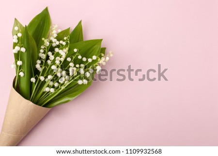 Festive flower lily of the valley composition in craft horn on the pastel pink background. Overhead view, may-lily bouquet with copy space

