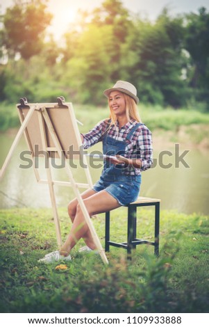 Beautiful girl draws a picture in the park