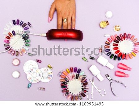 A set of cosmetic tools for manicure and pedicure on a weyt background. Gel polishes, nail files and clippers, and the lamp top view. Composition for card with a place for text