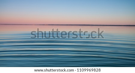 The turquoise lake at dawn.small symmetrical waves of blue and turquoise lake surface at dawn, red and orange and sky blue.