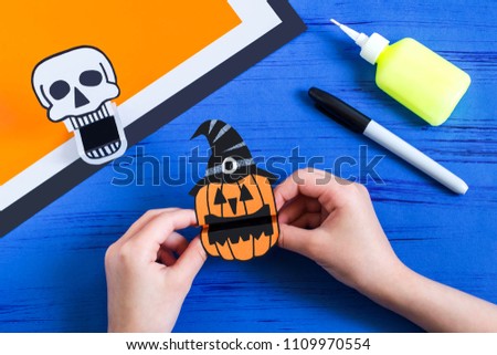 Child makes toothy paper toys (skull and Jack-o'-lantern) for Halloween. Children's art project. DIY concept. Step-by-step photo instruction. Step 12. Cut and fold toy Jack-o'-lantern