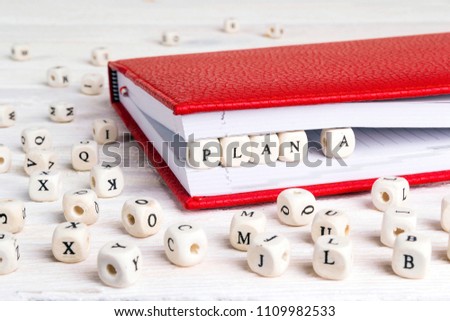 Word Plan A written in wooden blocks in red notebook on white wooden table. Wooden abc.