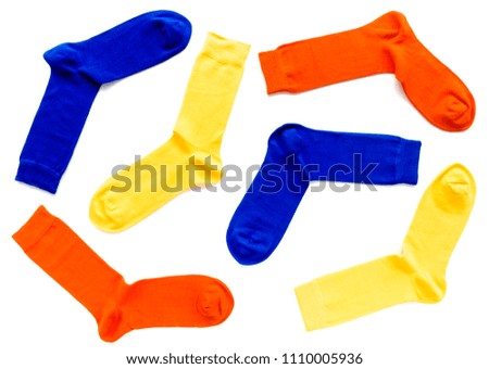 Flat lay of brightly colored trendy bamboo socks with hand linked toes in orange, yellow and blue colors on white background.