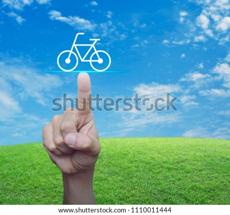 Hand pressing bicycle flat icon over green grass field with blue sky, Business service bike concept