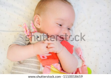 Cute baby hugs bright rabbit toy and smiles happily