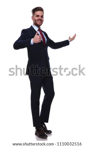 happy businessman in navy suit presenting and making ok sign while standing on white background