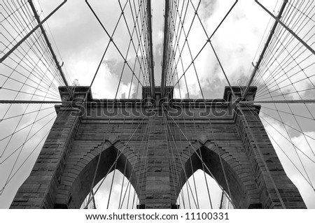Dramatic, symmetrical, black and white photo of the tower and cables of the Brooklyn Bridge in New York City.