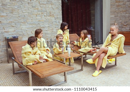 Large group of friends taking goog time with milk cocktails. Happy smiling boys and girs in yellow terry dressing gowns. Kids fashion concept