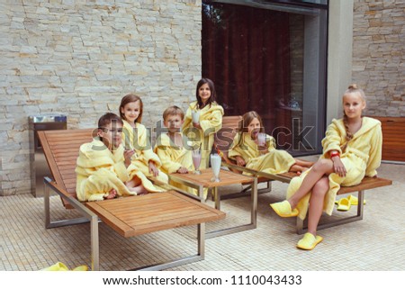 Large group of friends taking goog time with milk cocktails. Happy smiling boys and girs in yellow terry dressing gowns. Kids fashion concept