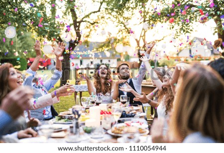 Bride and groom with guests at wedding reception outside in the backyard. Royalty-Free Stock Photo #1110054944