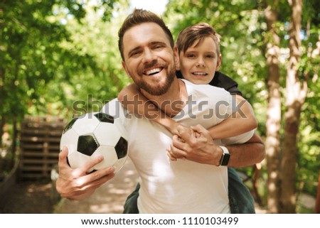 Picture of happy young father have fun with his little son outdoors in park nature with football ball.