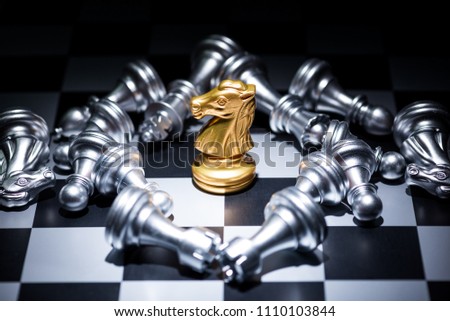 a gold chess surrounded by a number of silver chess pieces , business strategy concept