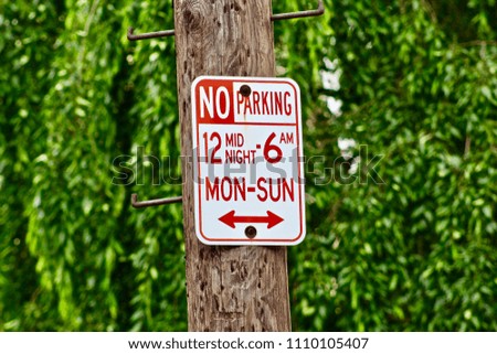 No Parking Sign On Wooden Telephone Pole Stating Midnight to 6am Monday Through Sunday