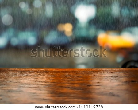 Wooden bar on blurred night car parking with bokeh background at coffee shop in raining day. Empty brown table for montage products with copy space.