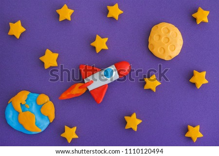 Space Rocket Flying To The Moon Through The Starry Sky. Space rocket and planet Earth with the Moon are made out of play clay (plasticine).