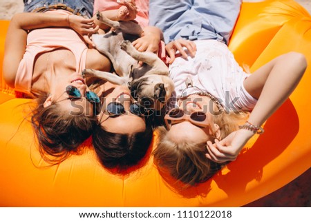 Three girls with small dog lying on pool mattress at the beach