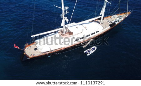 Aerial drone bird's eye view photo of luxury wooden deck sail boat docked in Greek island located in Aegean deep blue sea