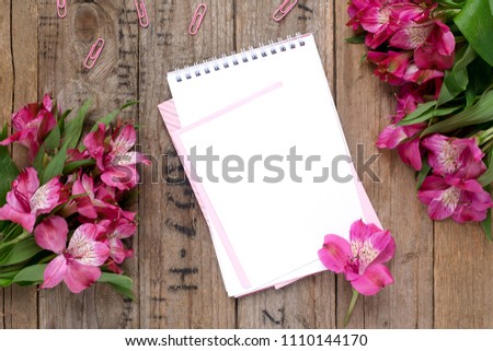 Empty white notepad with pink and white paper with flowerson vintage wooden table top view