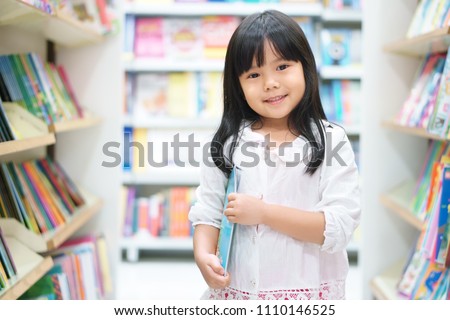 Asian children or kid girl happy smile and shopping or choose tale or story book on bookshelf in bookstore or library room at kindergarten school or nursery for learning and studying with education Royalty-Free Stock Photo #1110146525