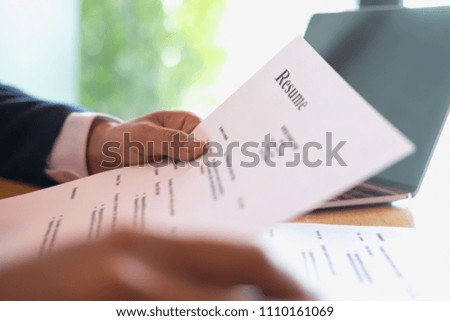 Businessman or HR Manager is reviewing Resume information on his wooden desk. Employment and recruitment concept