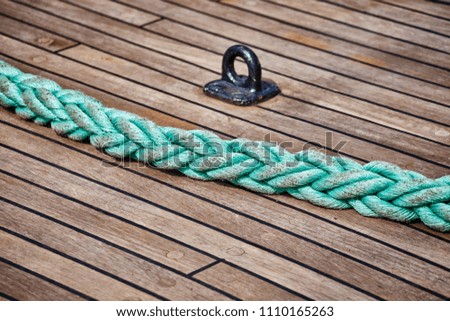 Green thick rope on an old sailing ship wooden deck, selective focus.