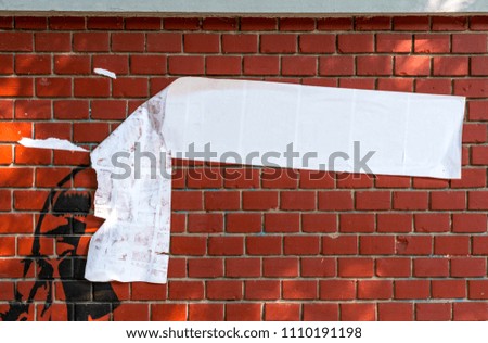 Half torn blank white banner with text space hanging on red brick wall
