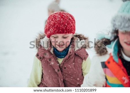 Close up shot of a little girl out in the snow with her friends.