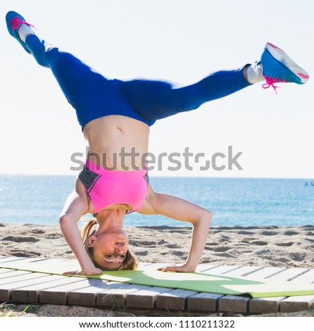 Woman 28-35 years old is practicing stretching on the beach near sea.  Royalty-Free Stock Photo #1110211322