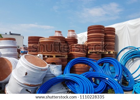 A warehouse of plastic pipes for various purposes, diameter and color under the open sky. Manufacture and sale of plastic products for construction works. Drainage and sewerage. 