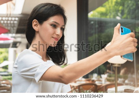 Happy young woman taking selfie in a restaurant terrace