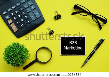 Top view yellow background desktop with black board sign write text B2B Marketing for business and finance concept.