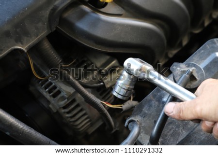 Closeup of instrument in technician's hand using for repairing old car engine with engine background.
