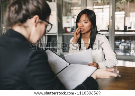 Photo from back of businesswoman interviewing and reading resume of nervous female applicant during job interview - business, career and placement concept Royalty-Free Stock Photo #1110306569