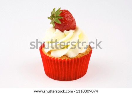 Red cupcake with white cream decorated with strawberry on white background. Picture for a menu or a confectionery catalog.
